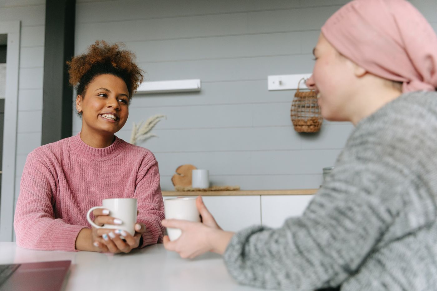 Two women talking over coffee at a home table.